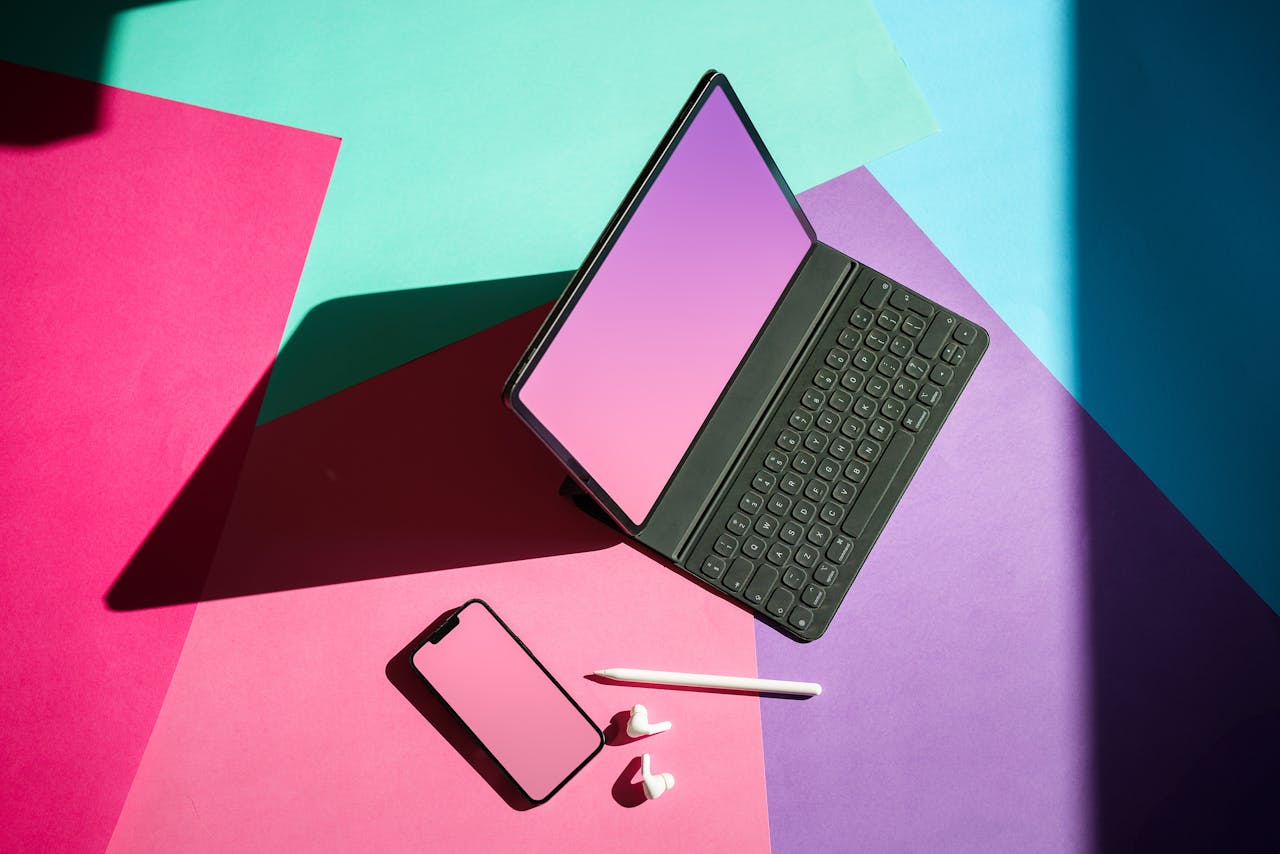 Vibrant flat lay featuring a tablet, smartphone, and stylus on a colorful background.